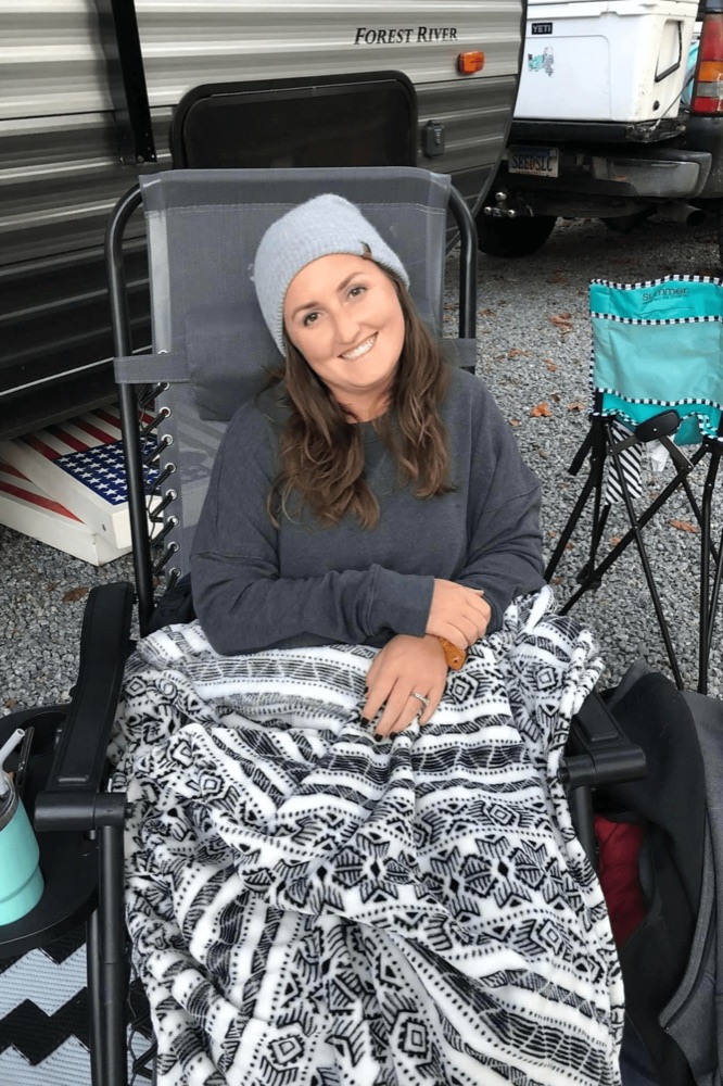 Angela smiling outdoors on a camping trip, remembered by her family as the heart behind AES Cancer Foundation.